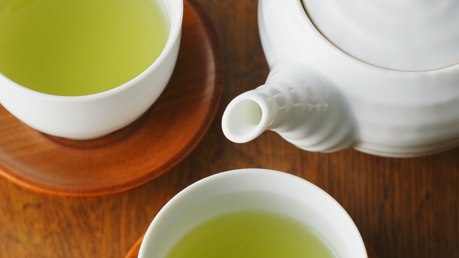 A cup of green tea beside coffee beans