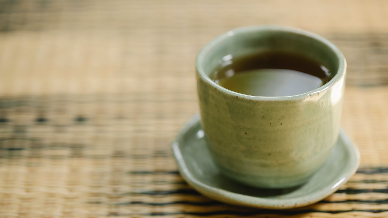 A clear glass cup of freshly brewed green tea
