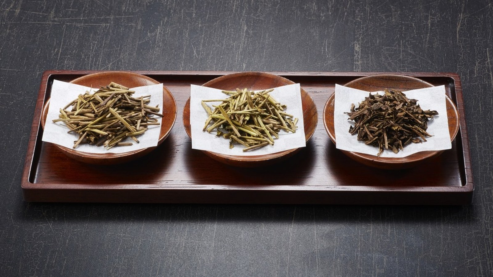 Roasted Japanese teas — kukicha, bocha and hojicha leaf — on a wooden tray
