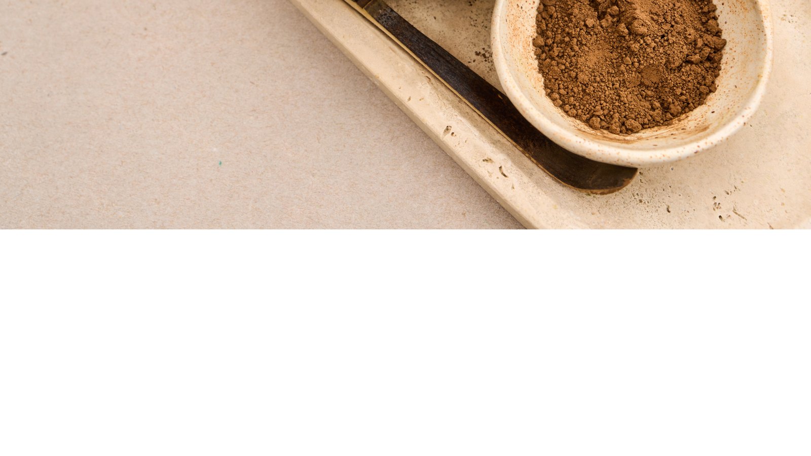 Reddish-brown hojicha powder in a bowl beside a bamboo whisk