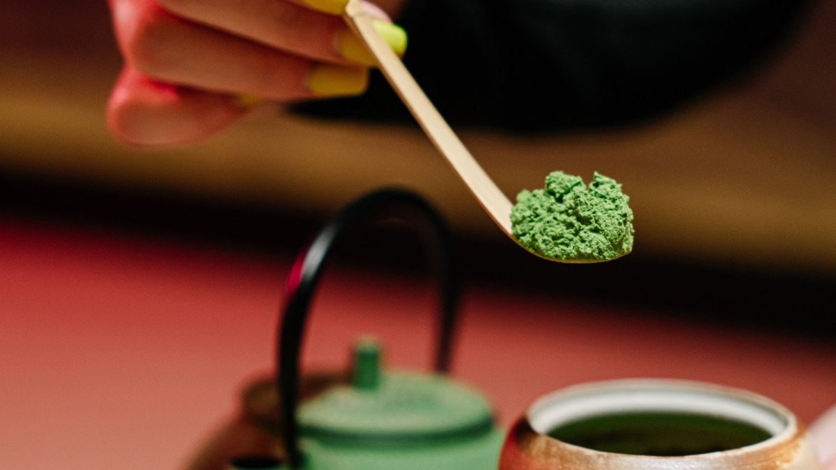 Whisking a bowl of frothy green matcha with a bamboo whisk