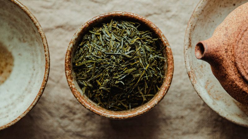 Powdered green tea beside loose leaves