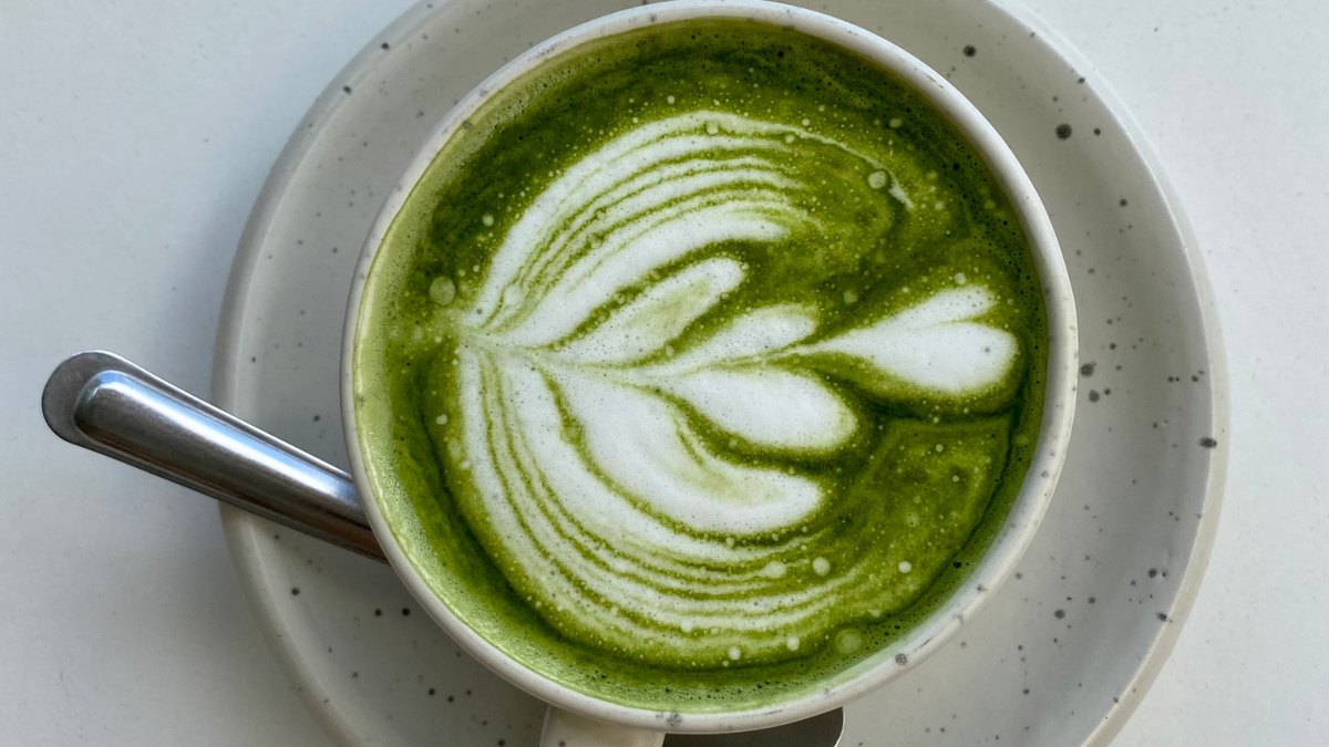 A matcha latte and green tea treats arranged on a wooden table
