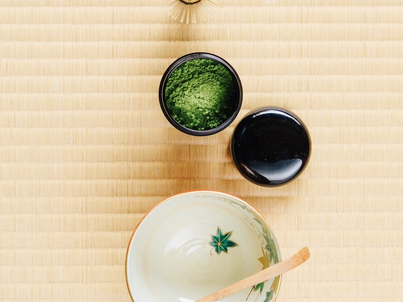 Green tea leaves beside matcha powder