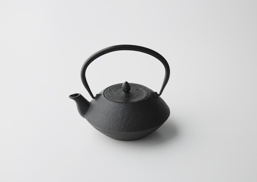 A traditional black Nambu cast iron tetsubin kettle with a handle and spout