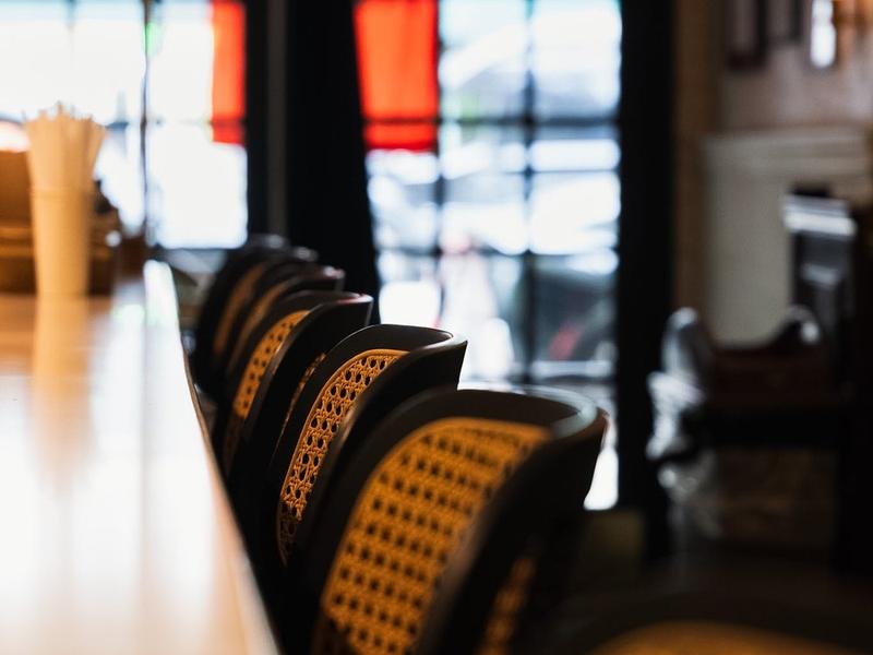 A row of cane-backed chairs along the counter, morning light through the door